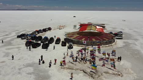 Aerial-Orbits-Restaurant-Und-Plaza-Of-Flags,-Salzsee-Von-Uyuni,-Bolivien