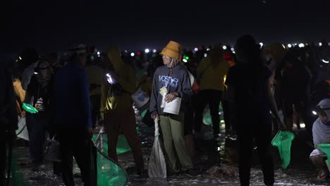 Gente-En-La-Orilla-Del-Mar-Por-La-Noche-Con-Linternas-Y-Redes-De-Pesca-Atrapando-Gusanos,-Festival-Bau-Nyale-Indonesia