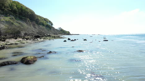 Low-aerial-shot-over-the-sea-showing-the-blue-sea-and-rocky-coast-line,-shot-on-a-bright-sunny-day