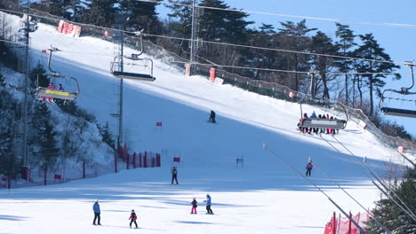 Skiers-Ride-Chair-Lift-and-Skiing-Down-the-Run-at-Alpensia-Ski-Resort---aerial-view