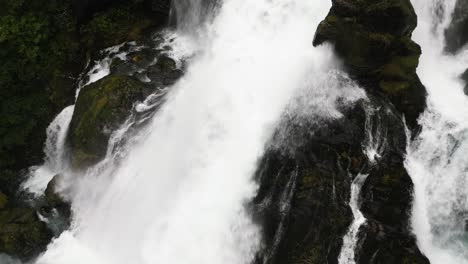 close-up-of-a-huge-waterfall-in-a-green-forrest,-norway,-nature,-drone