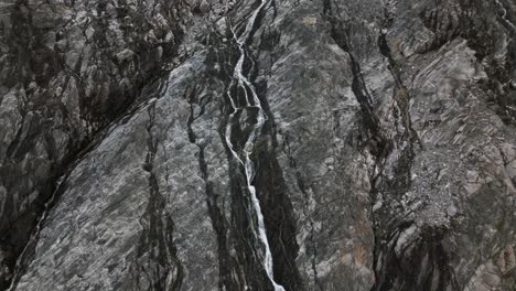 Cascada-De-Un-Glaciar-En-Una-Empinada-Pared-Rocosa-En-Las-Montañas,-Noruega,-Europa,-Drone