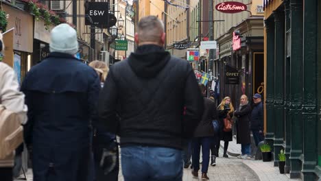 Families-walk-sightseeing-in-Old-Town-on-cobblestone-street-on-cold-day,-Stockholm