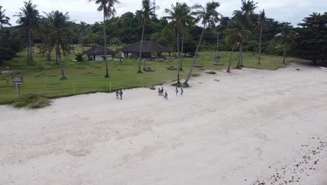Filipino-Kids-on-Remote-Island-Walking-to-School-on-Beach,-Drone-Shot