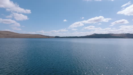 Antena-Baja-Sobre-El-Agua-Del-Lago-Rural-En-Un-Día-Claro-Y-Soleado