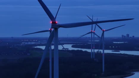 Rotating-Wind-Turbines-Next-To-River-Oude-Maas-At-Dusk---Aerial-Drone-Shot