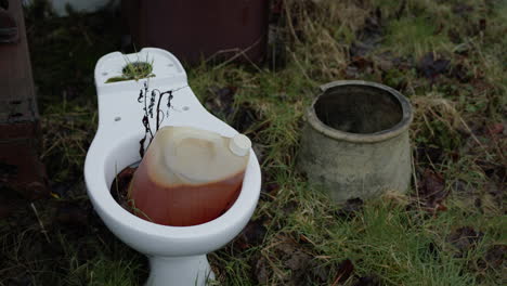 Abandoned-white-toilet-with-dirty-bottle-of-water-in-it