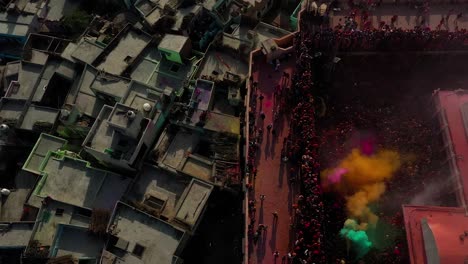 AERIAL-DRONE-VIEW-The-drone-camera-is-moving-from-the-top-of-the-temple-to-the-right-side,-showering-color-on-the-processions-playing-below-from-the-terrace