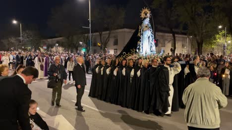 Toma-De-La-Imagen-De-La-Virgen-Con-Sus-20-Portadores-Con-Vestimentas-De-La-Cofradía-Todos-Al-Paso-Común-Detrás-De-Los-Ministros-O-Sacerdotes-Todo-Transcurre-De-Noche-Hay-Reporteros-Filmando