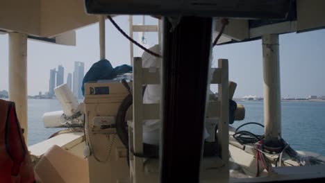 Rückansicht-Des-Kapitäns-Eines-Kreuzfahrtschiffs,-Das-Im-Persischen-Golf-Segelt,-Mit-Der-Skyline-Von-Abu-Dhabi-Im-Hintergrund