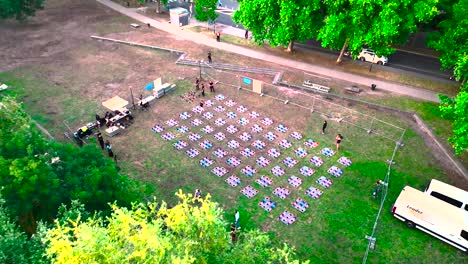 Hundreds-of-drones-being-prepared-for-nighttime-display-at-Wine-Fair,-Aerial-dolly-out-shot