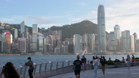 Man-Sieht-Menschen-An-Der-Victoria-Waterfront,-Im-Hintergrund-Sieht-Man-Die-Skyline-Von-Hongkong