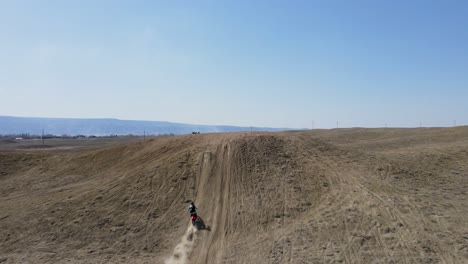 An-action-packed,-slow-motion-drone-shot-of-two-motocross-riders-hitting-a-big-hill-jump,-in-the-desert-like-terrain-of-Grand-Valley-OHV-area,-located-in-Grand-Junction,-Colorado