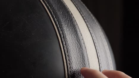 Close-up-of-a-hand-running-fingers-over-textured-black-leather,-emphasizing-touch-and-detail