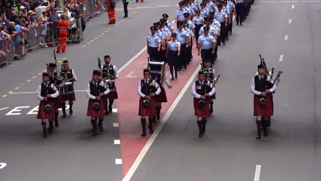 Dudelsackspieler-In-Traditioneller-Kleidung-Marschieren-Die-Straße-Entlang,-Nehmen-An-Der-Feierlichen-Anzac-Day-Parade-Teil-Und-Ehren-Die-Opfer-Der-Vergangenheit,-Stadt-Brisbane