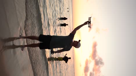 Vertical---Creador-De-Contenido-Volando-Drone-En-La-Playa-De-Waikiki-Al-Atardecer-En-Oahu,-Hawaii