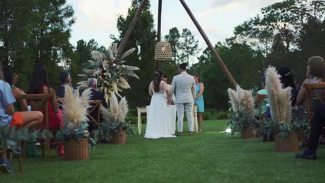 Ceremonia-De-Boda-En-Un-Campo-Con-Decoración-Boho,-La-Novia-Y-El-Novio-Están-Parados-Frente-Al-Altar