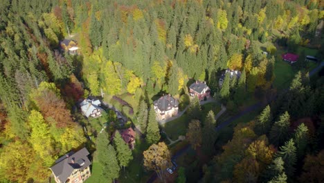 órbita-Aérea-Sobre-El-Hermoso-Pueblo-Escondido-En-El-Bosque-De-Montaña-En-Otoño