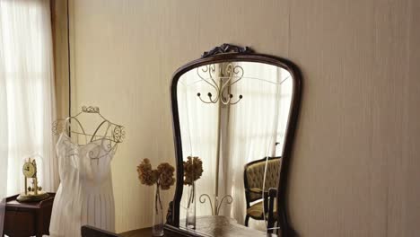 Coat-hanger-reflected-in-the-mirror-on-a-wall-in-a-room-with-antique-decoration