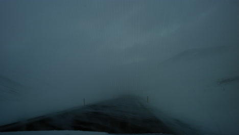 Slow-motion-driving-pov-as-windy-snow-covers-asphalt-road-in-Iceland