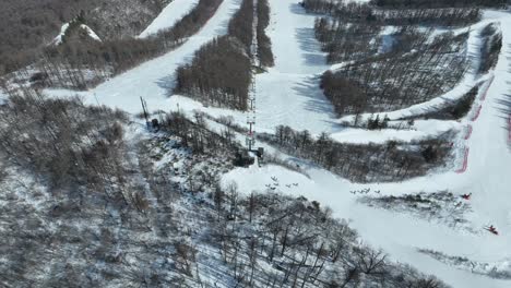 Establishing-pull-away-pan-up-shot-from-above-mountain-peak-summit,-camera-revealing-large-ski-area