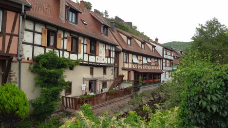 Bunte-Häuser-Des-Dorfes-Kayserberg-Im-Frühherbst-In-Der-Nähe-Des-Flusses-Weiss