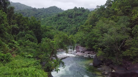 Viewed-from-a-slow-motion-aerial-perspective,-the-Babinda-Boulders-in-Cairns,-Australia-unveil-swift-streams-and-dense-forests-entwined-with-massive-granite-formations,-a-tranquil-sight