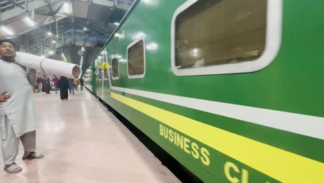 Green-train-arrives-at-Lahore-station-and-people-wait-to-board