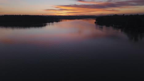 Sunrise-early-aerial-silhouette-over-Georgia-lake-with-birds-flying