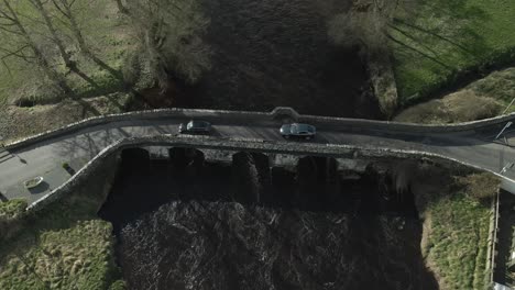 Cars-crossing-an-ancient-stone-bridge-over-a-river-in-Trim,-Ireland,-aerial-view