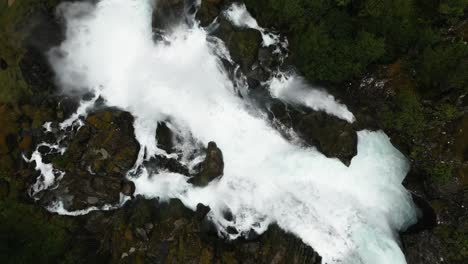 top-view-of-a-huge-waterfall-in-a-green-wet-forrest,-norway,-nature,-drone