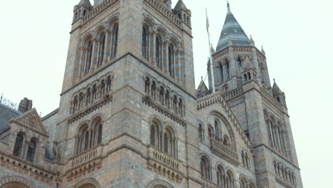 Tilt-up-shot-of-exterior-architecture-of-Natural-History-Museum-during-daytime-in-London,-England