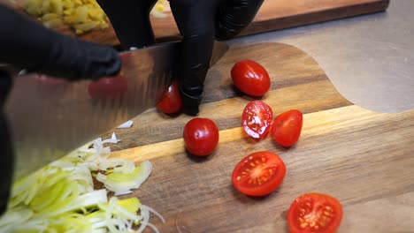 El-Chef-Corta-Tomates-Cherry-En-Gajos-Sobre-Una-Tabla-De-Cortar