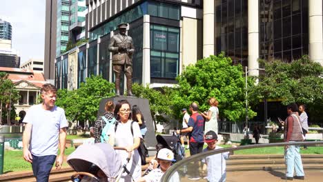 People-gathered-in-front-of-Major-General-Sir-William-Glasgow-Memorial-statue,-paying-tribute-to-those-who-served,-adorned-with-flowers-and-wreaths-at-Post-office-square-on-Anzac-Day