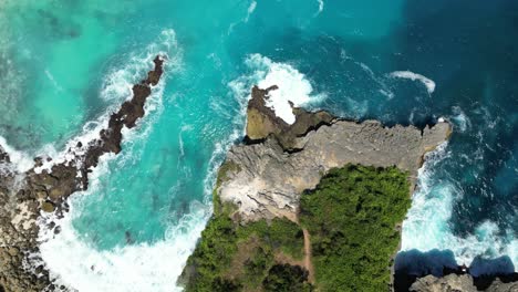 Aerial-shot-of-ocean-waves,-stone-cliff-and-ocean-landscape-in-Bali,-Indonesia-in-4K