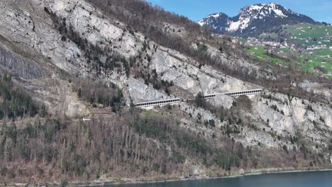 Camera-pan-with-a-view-over-the-Walensee-in-Switzerland,-rocks-and-mountains-and-blue-lake---Amden,-Weesen,-Glarus