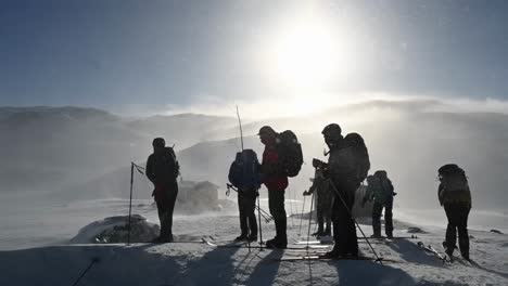 Group-of-people-having-a-break-together-during-snowy-mountain-hiking-adventure