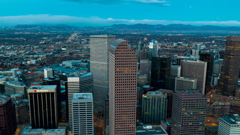 Illuminated-Denver-CBD-cityscape-in-morning,-aerial-hyperlapse-view