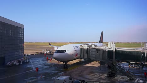 Air-Canada-aircraft-parked-at-airport-terminal-gate-with-loading-bridge-moving-and-positioning-to-passenger-doors,-Rome-in-Italy