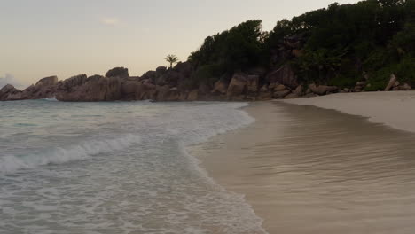 Waves-crashing-onto-the-sandy-beach-during-sunset