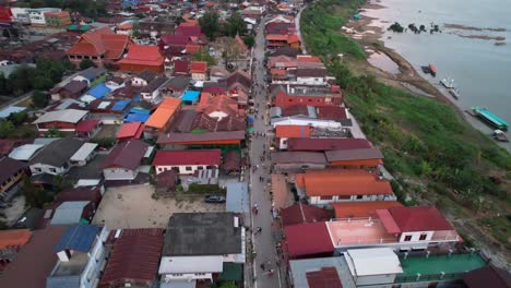 Aerial-shot-of-a-street-and-resident-houses-in-the-Chiang-Khan-District-alongside-the-Mekong-River-in-Thailand,-drone-fly-backward