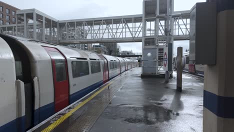 Ankunft-Des-Zuges-Der-Piccadilly-Line-Am-Bahnsteig-Des-Acton-Town-Bahnhofs-An-Einem-Nassen,-Bewölkten-Tag