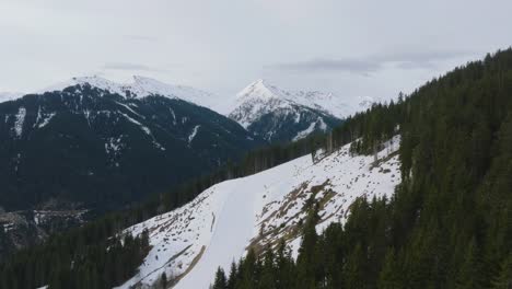 Snow-covered-peaks-at-Austrian-ski-resort-Saalbach-Hinterglemm-,-pine-trees-dotting-the-landscape,-aerial-view