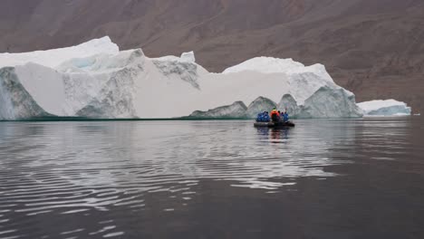 Touristen-Im-Boot-Vor-Einem-Riesigen-Eisberg-Im-Kalten-Wasser-Des-Isfjords,-Spitzbergen,-Norwegen