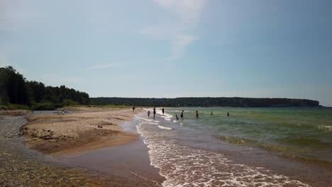 Families-swim-and-play-by-sunny-sand-beach-on-Gotland-in-Sweden,-slomo