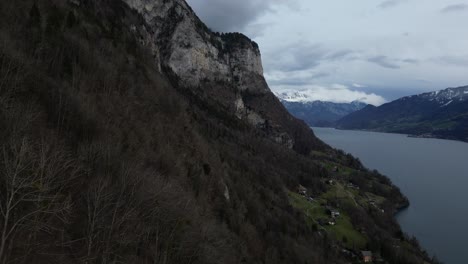 Forward-drone-shot-of-snow-covered-mountains-with-lake-flowing-by-in-Walensee,-Switzerland