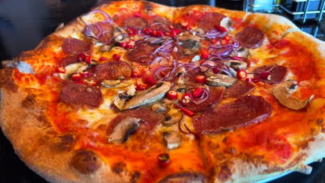 Traditional-Italian-spicy-pepperoni-pizza-with-fresh-chili-peppers,-red-onion-and-mushrooms,-real-authentic-Neapolitan-pizza,-delicious-food,-4K-shot