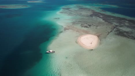 Drone-shot-small-atoll-surrounded-by-bright-turquoise-ocean,-Los-Roques-world-heritage