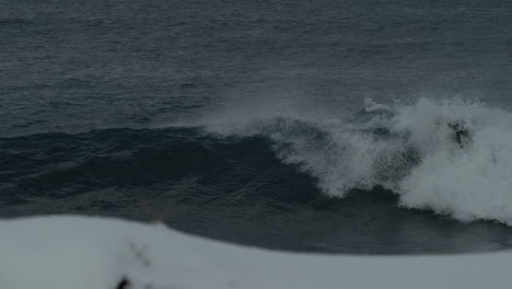 Surfer-glides-along-top-of-strong-arctic-wave-quickly-cutting-back-and-spraying,-tracking-follow