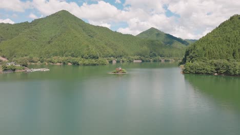 Paisaje-Panorámico-De-La-Cordillera-En-Un-Prístino-Lago-Japonés-Color-Turquesa-Templo-Santuario-Religioso-Sintoísta-Construido-En-Medio-Del-Agua,-Verano-En-Japón,-Horizonte-Matutino